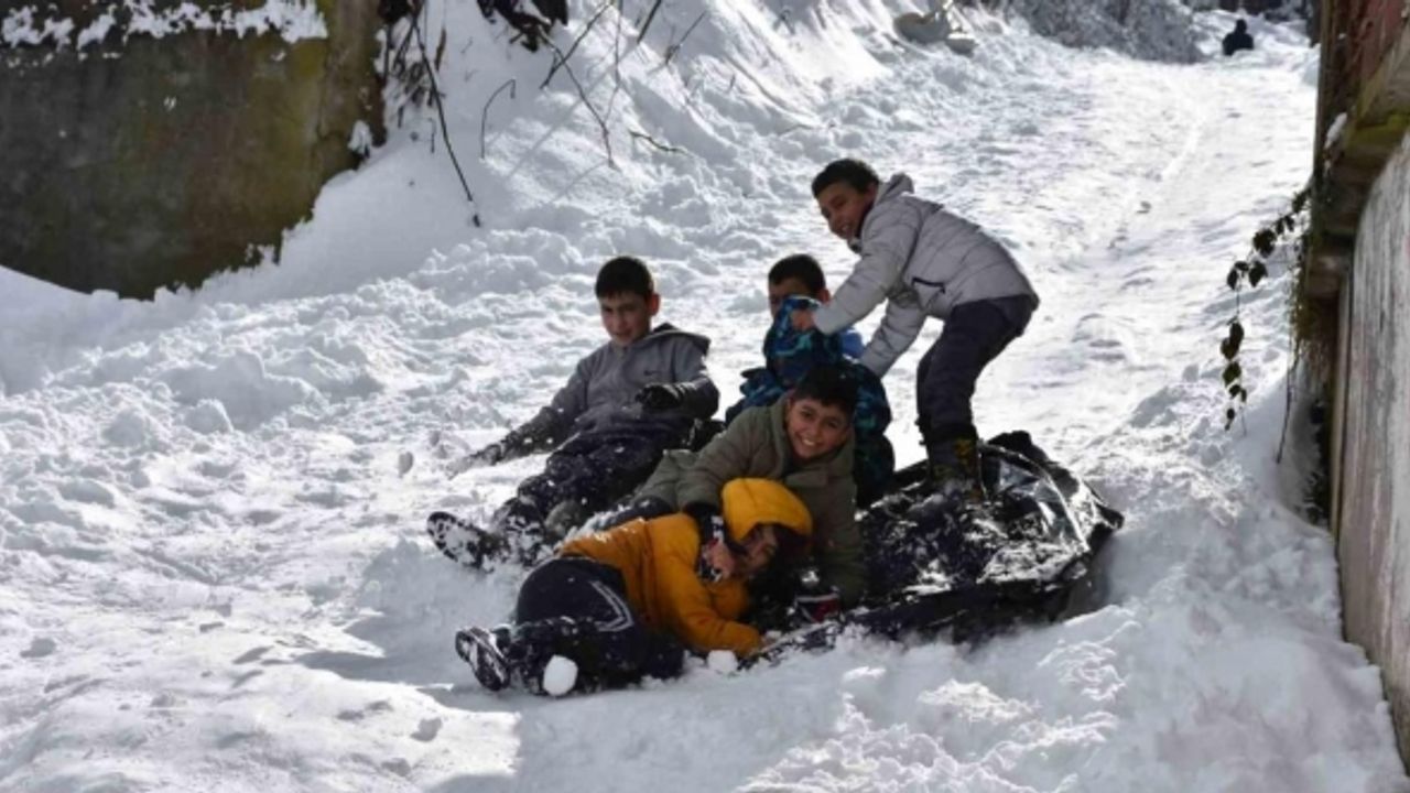 Beyaz örtüyle kaplanan mahallede poşetlerle kayarak eğlendiler