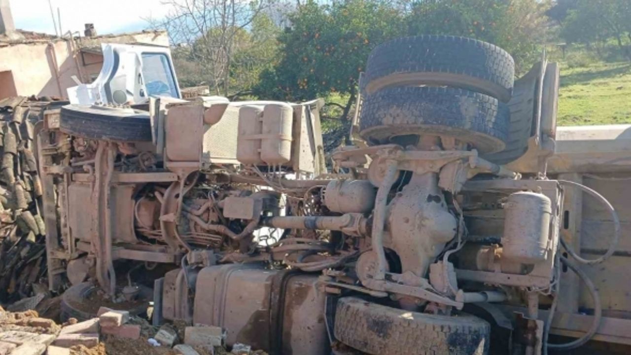 Otobüse çarpan kum yüklü kamyon, bir evin  bahçesine devrildi